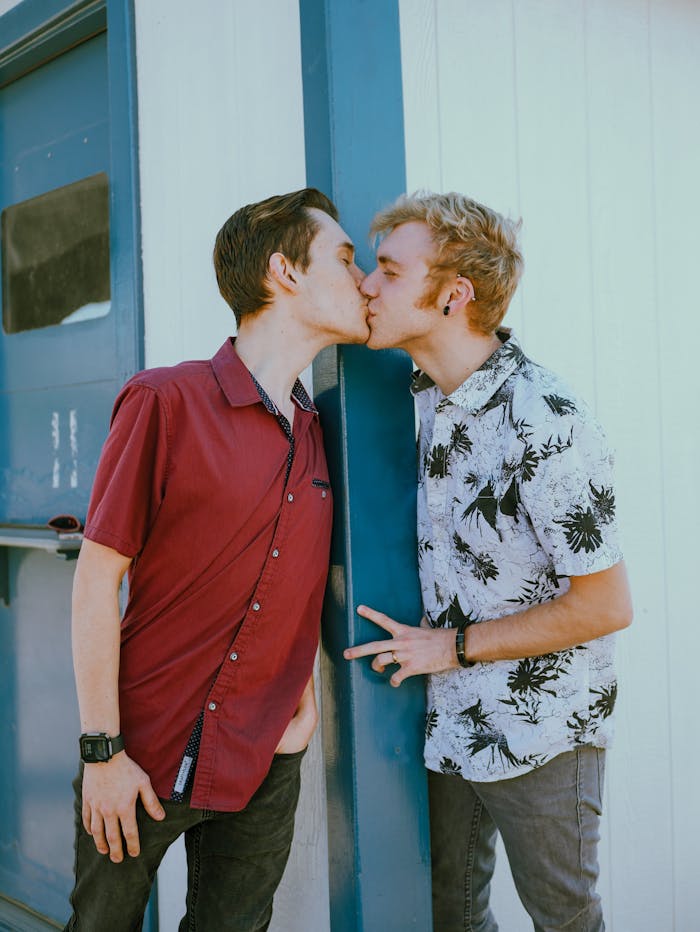 A young couple sharing an affectionate kiss outside an urban setting, representing love and togetherness.
